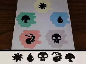 A neat MTG 3D print project are these Mana Symbol Badges. Shown in the photo are the 5 badges on top of color swatches that match the mana symbol and also all 5 badges lined up in a row below that.