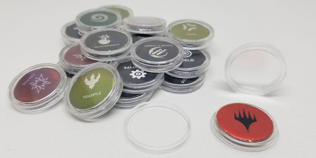 Some of the punch-out ability counters I keep in my MTG backpack are pictured. The punch-out ability counters are placed inside penny coin capsules.